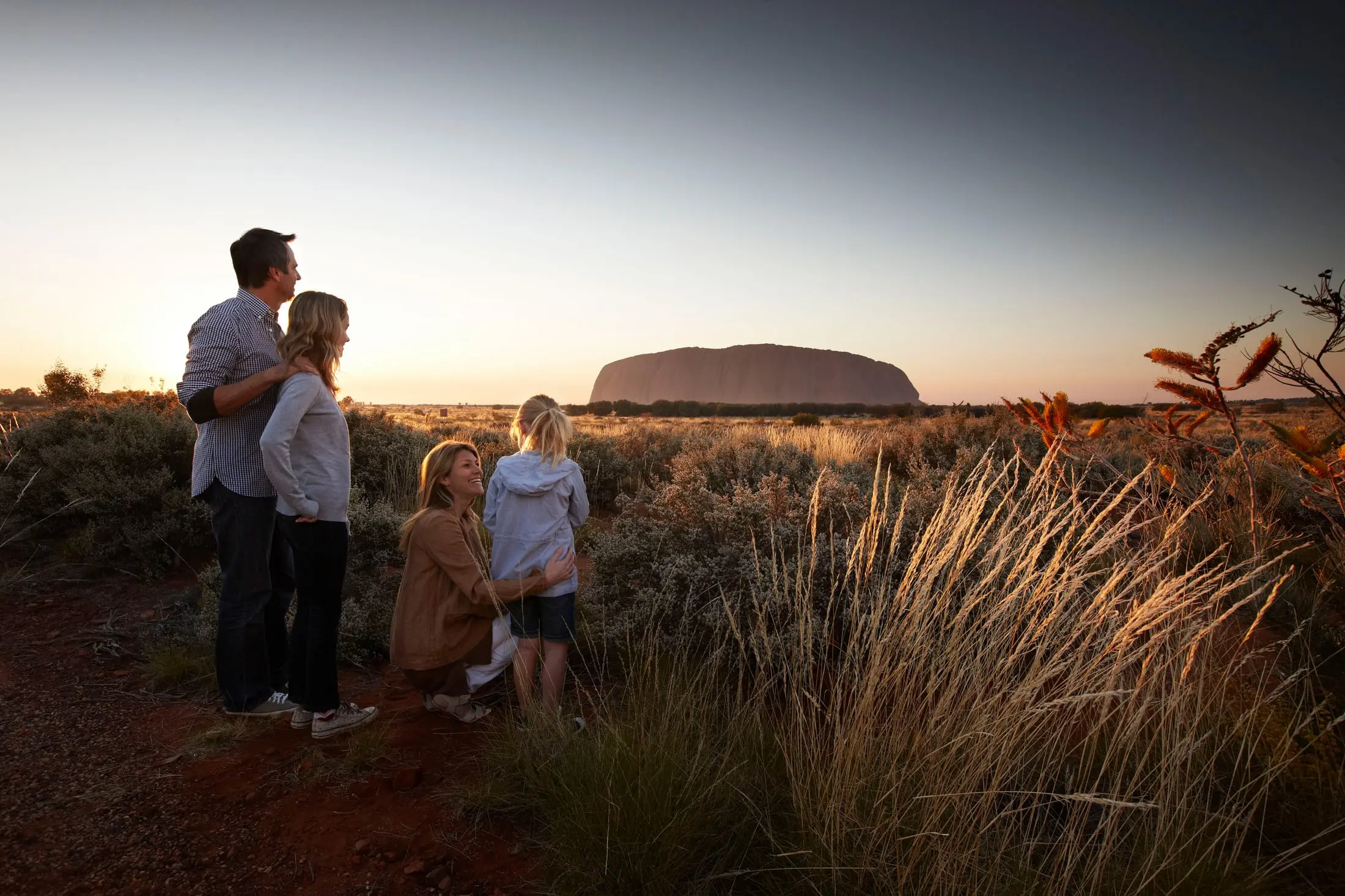 A family looking at Uluru at sunset