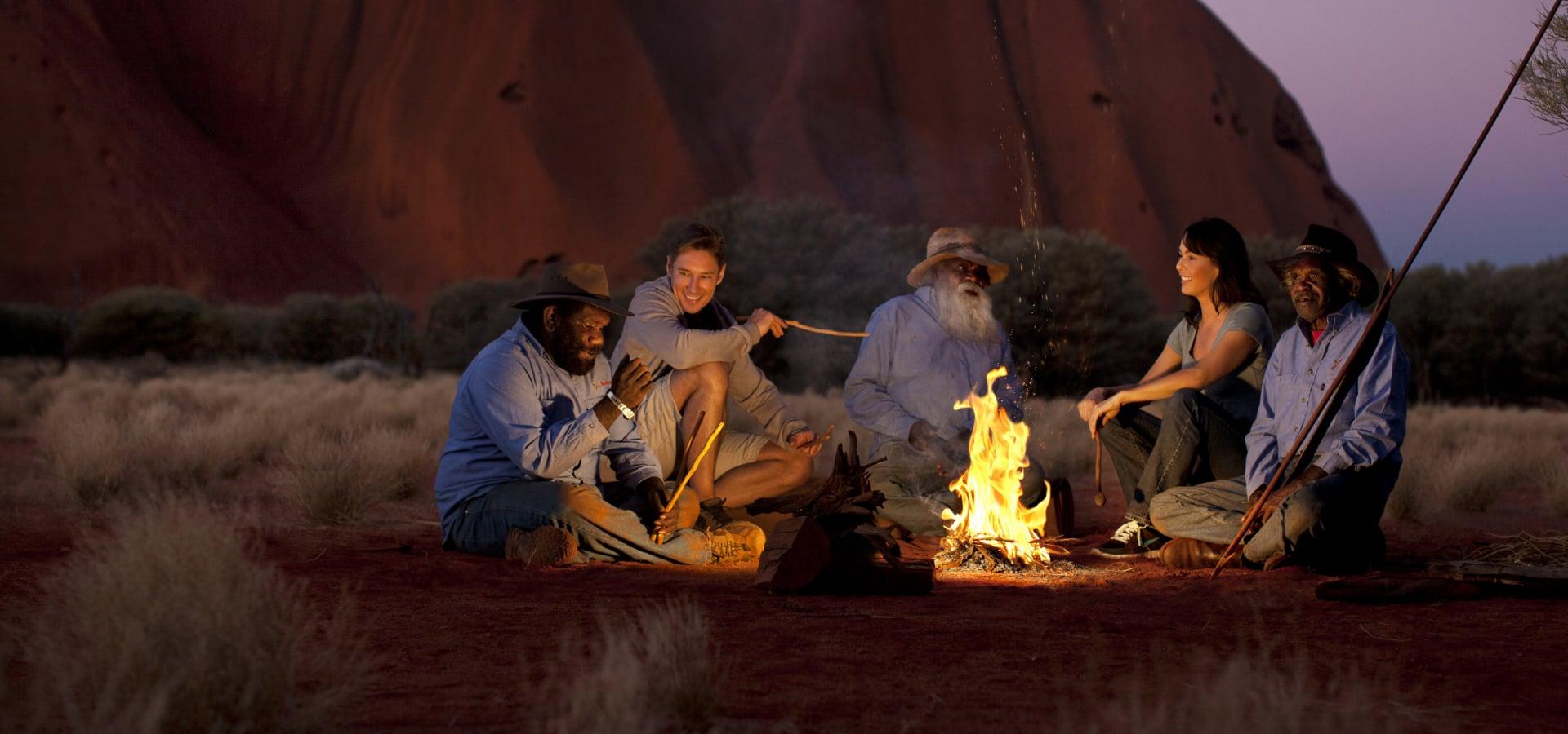 A group sitting around a campfire at the base of Uluru