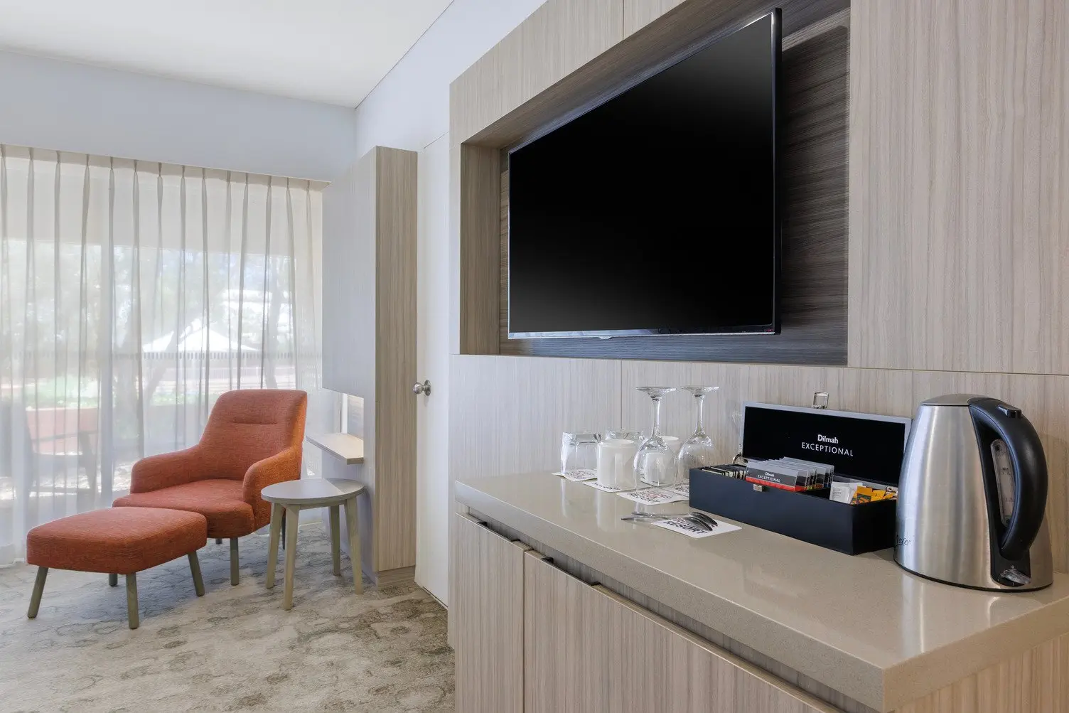 Bar Fridhe with kettle, tea and coffee sachets, TV mounted to wall and orange sitting chair