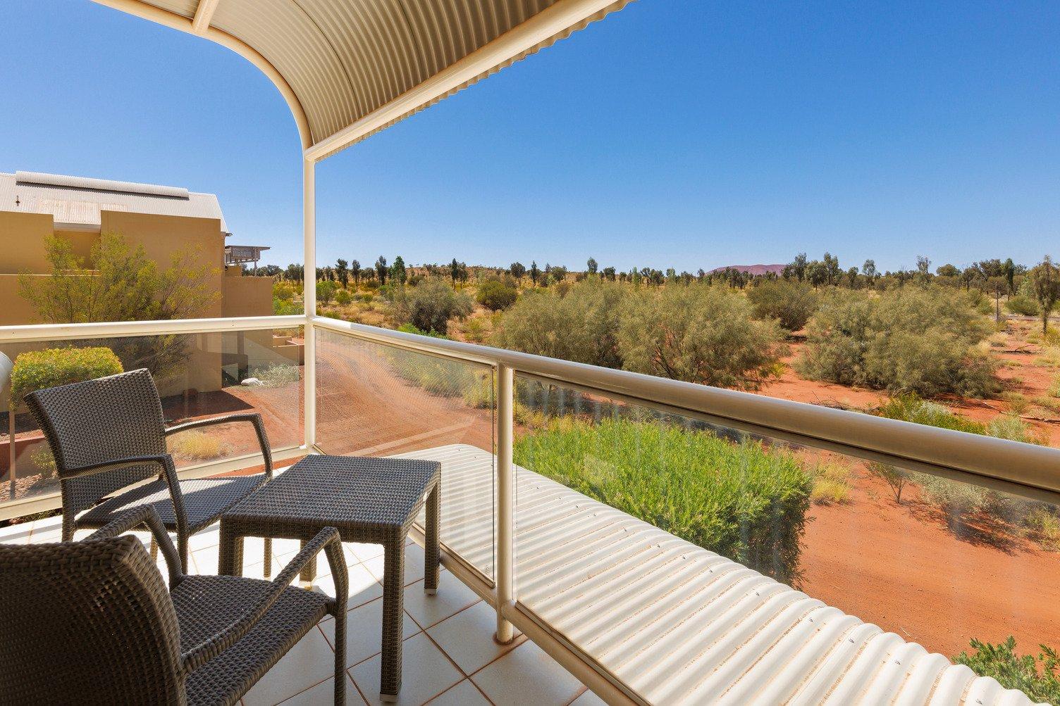 Balcony with two chairs looking out onto the desert lanscape with uluru in the distance