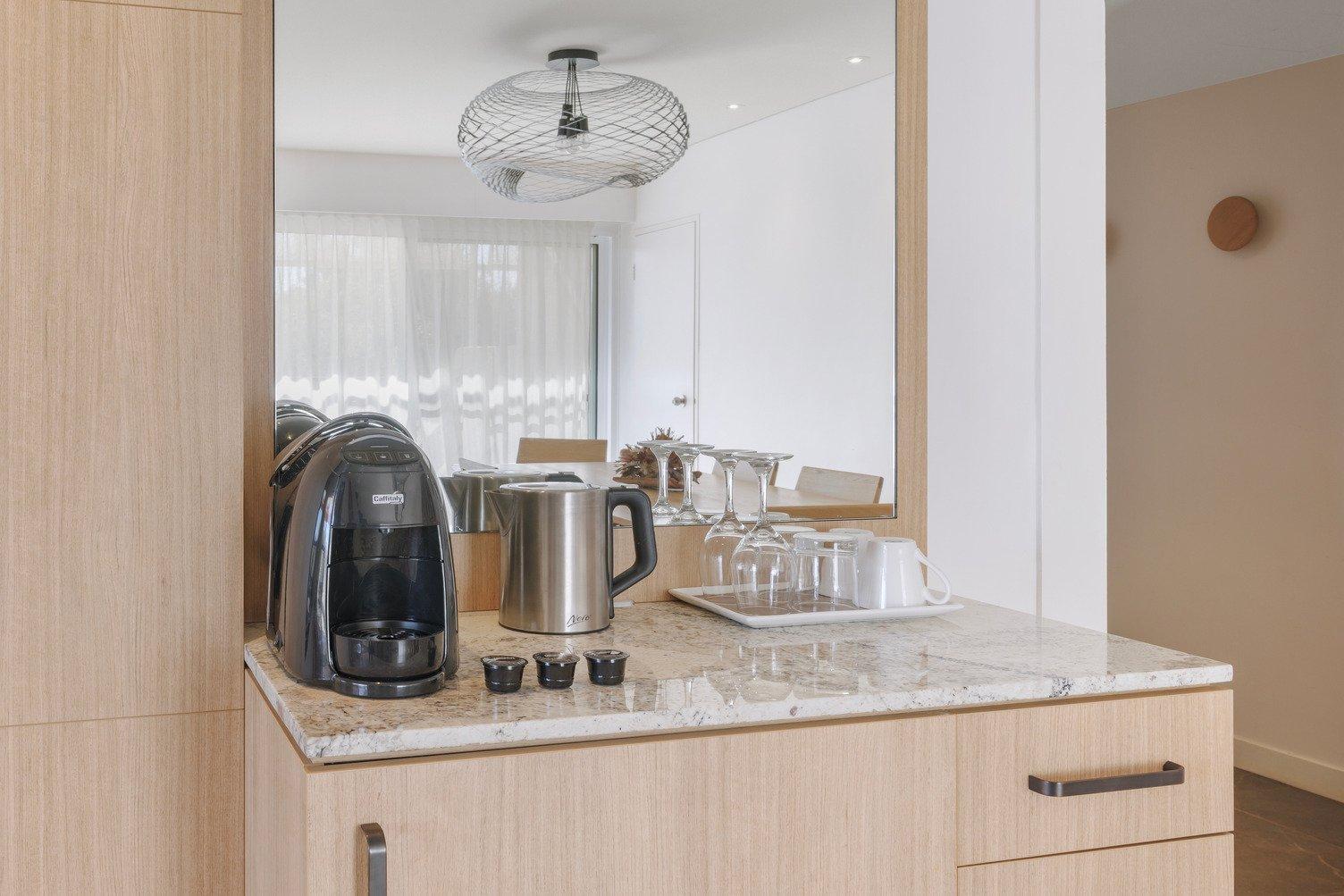 Kitchenette featuring a pod coffee machine, kettle, mugs and glasses