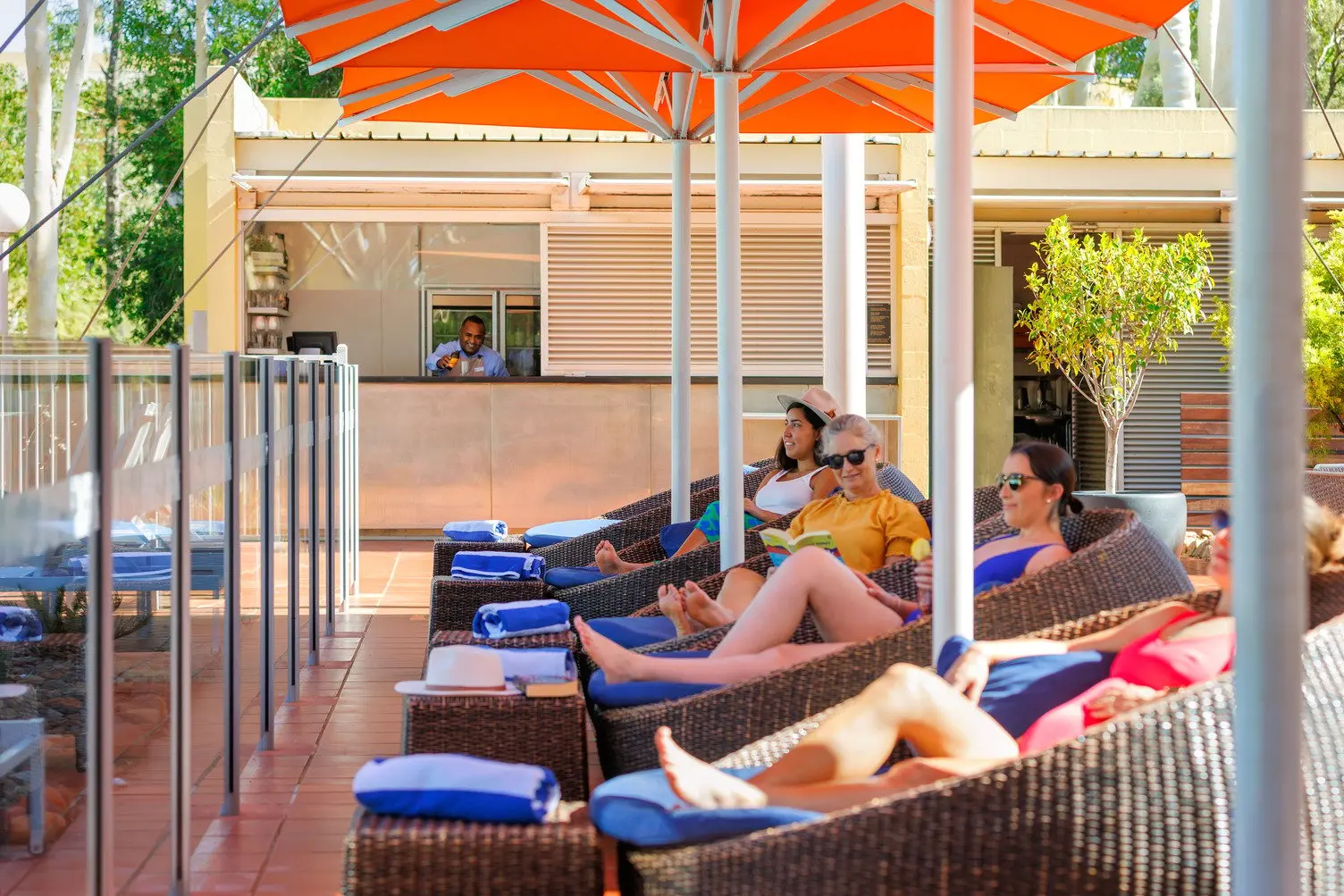 Four females relaxing in egg chairs at Pira Pool Bar while a bar attendant pours a ginger beer into a glass