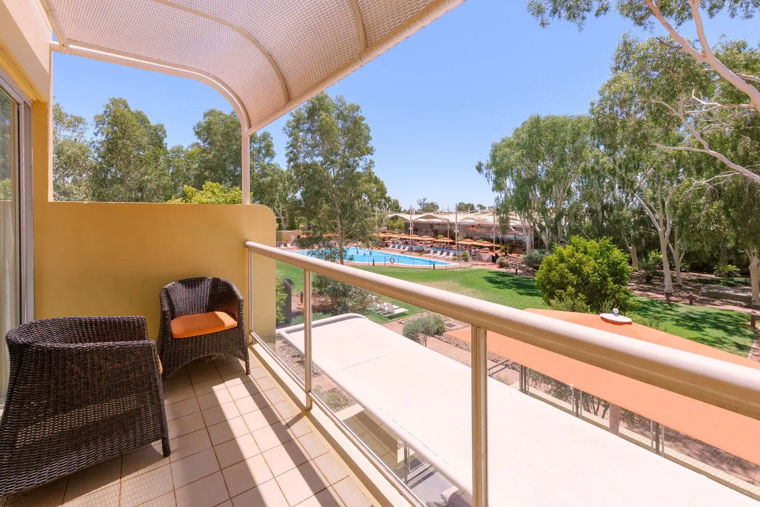 View of swimming pool and gardens from Superior room balcony with two comfortable chairs