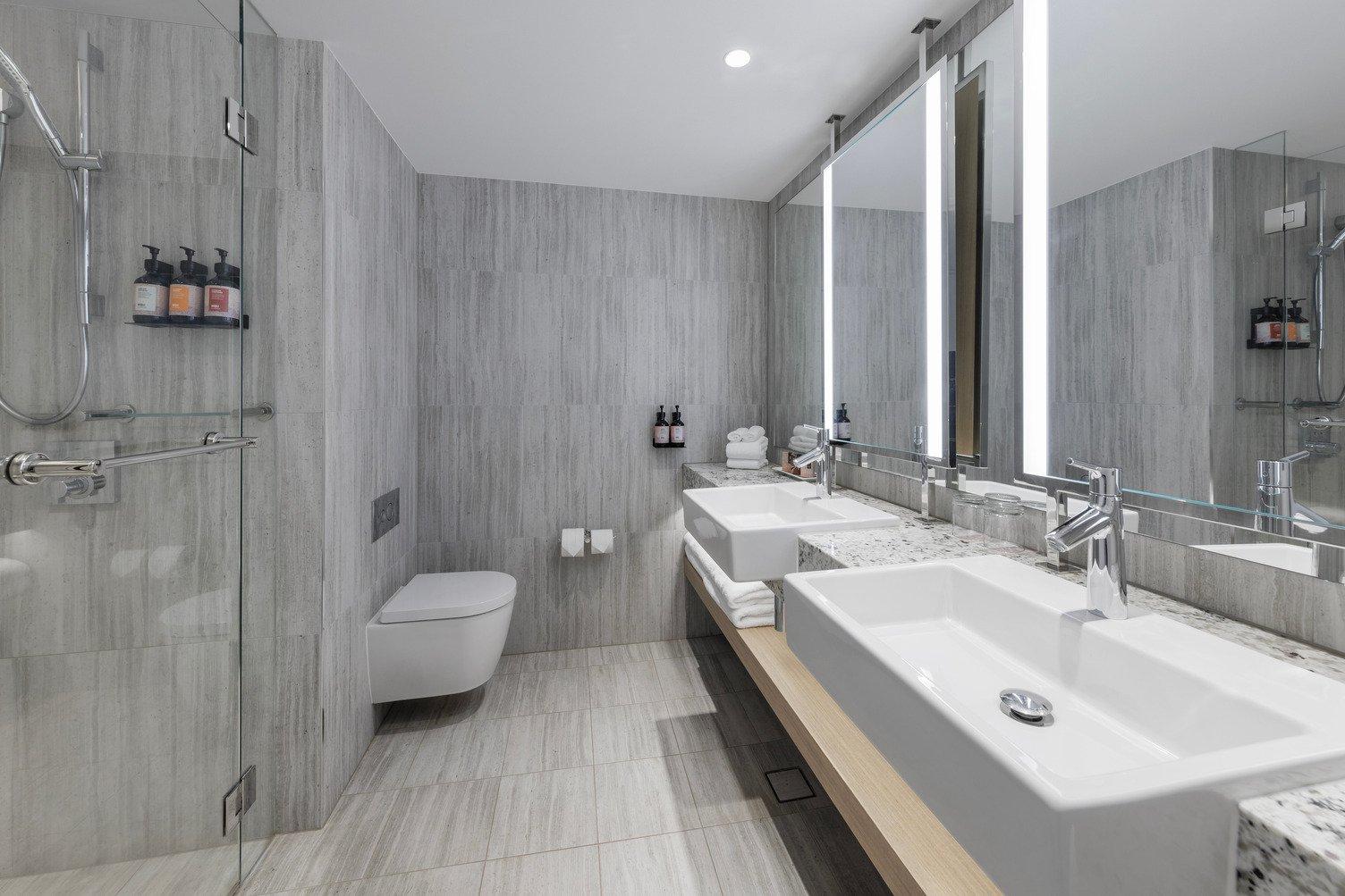 Modern bathroom with double sink, toilet and shower with Wiru Shampoo and Conditioner
