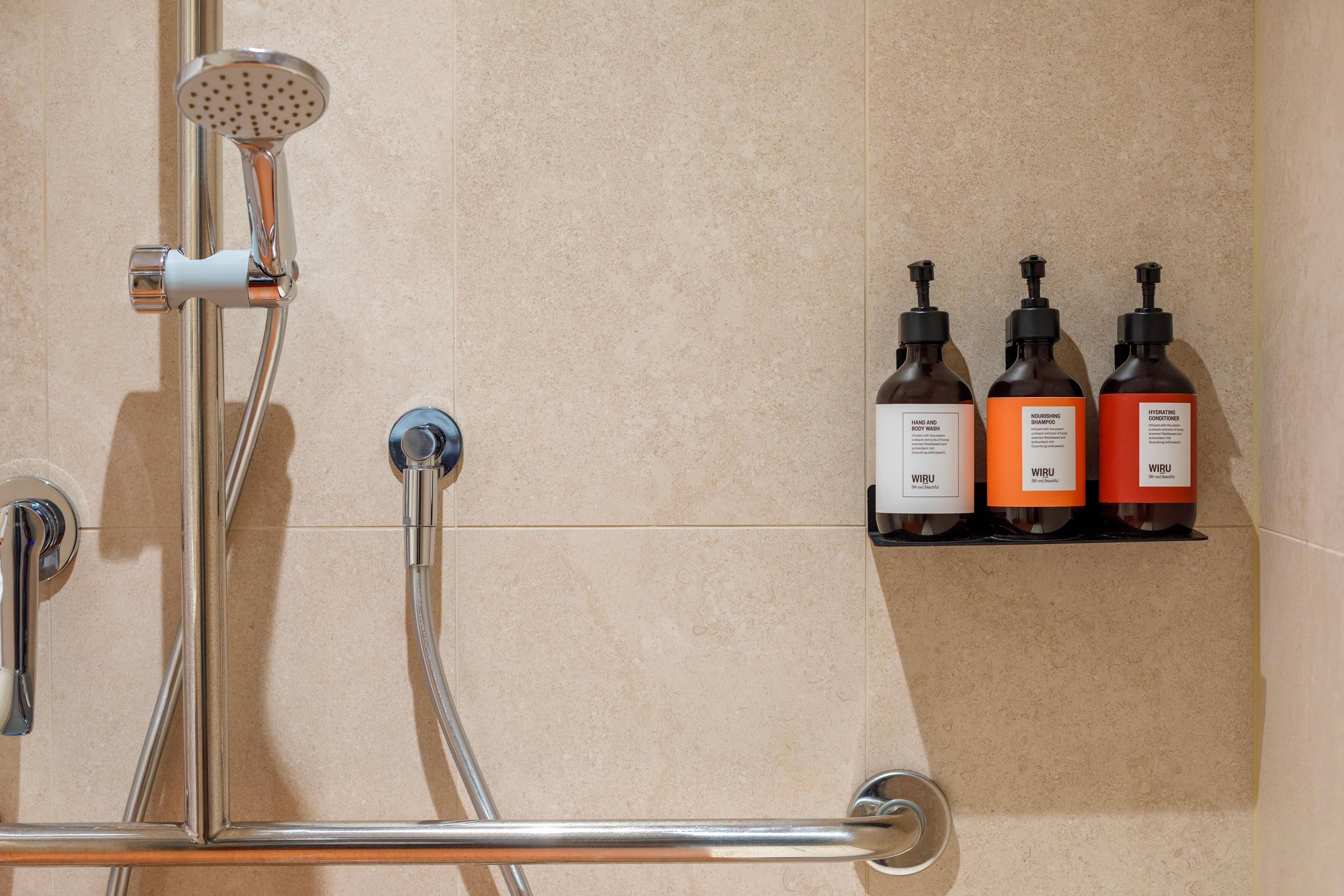 close up shot of body wash, shampoo and conditioner by 'Wiru' and a shower head