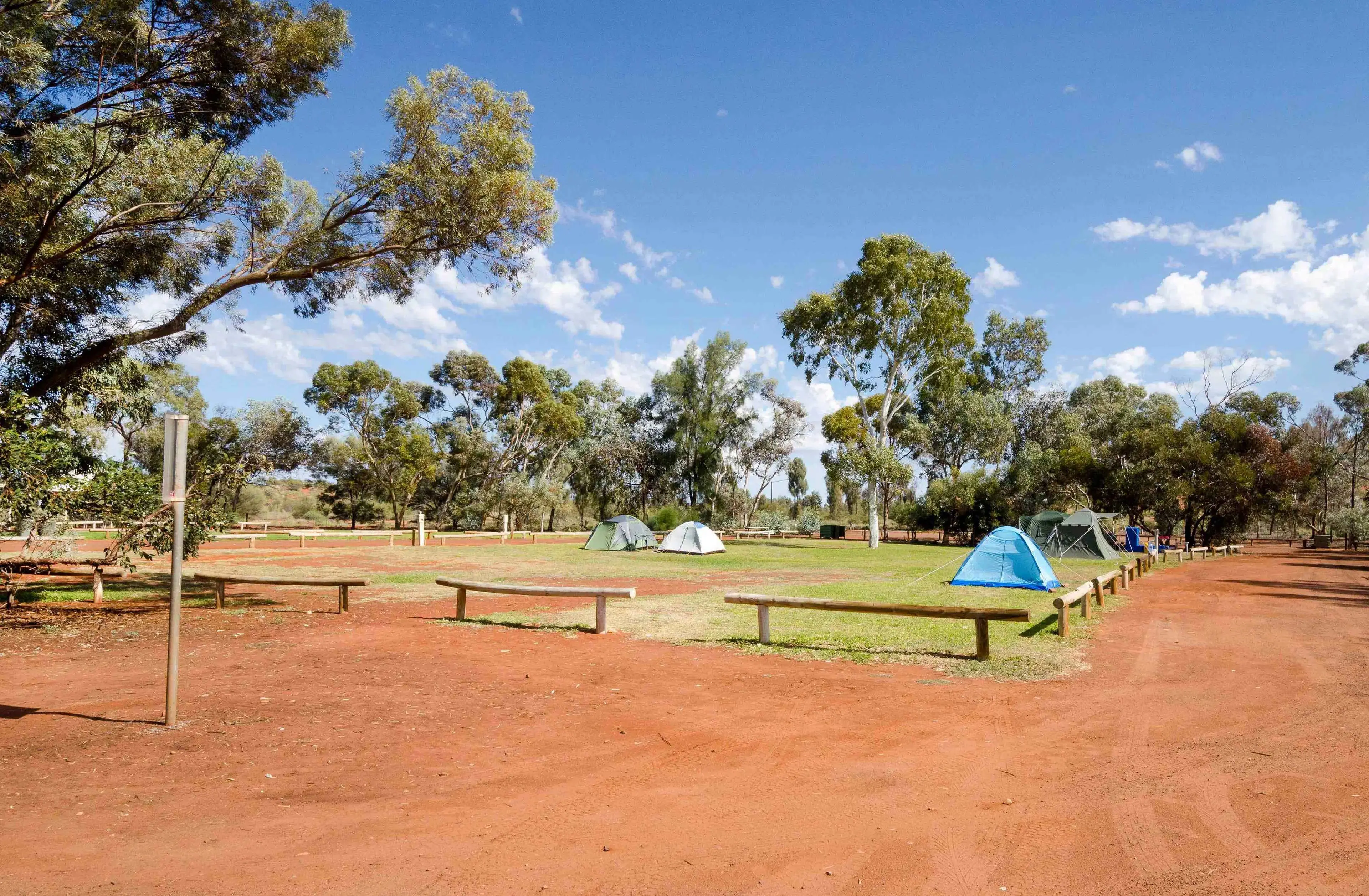 a few tents set up on the tent site with grass and red dirt surrounding the area