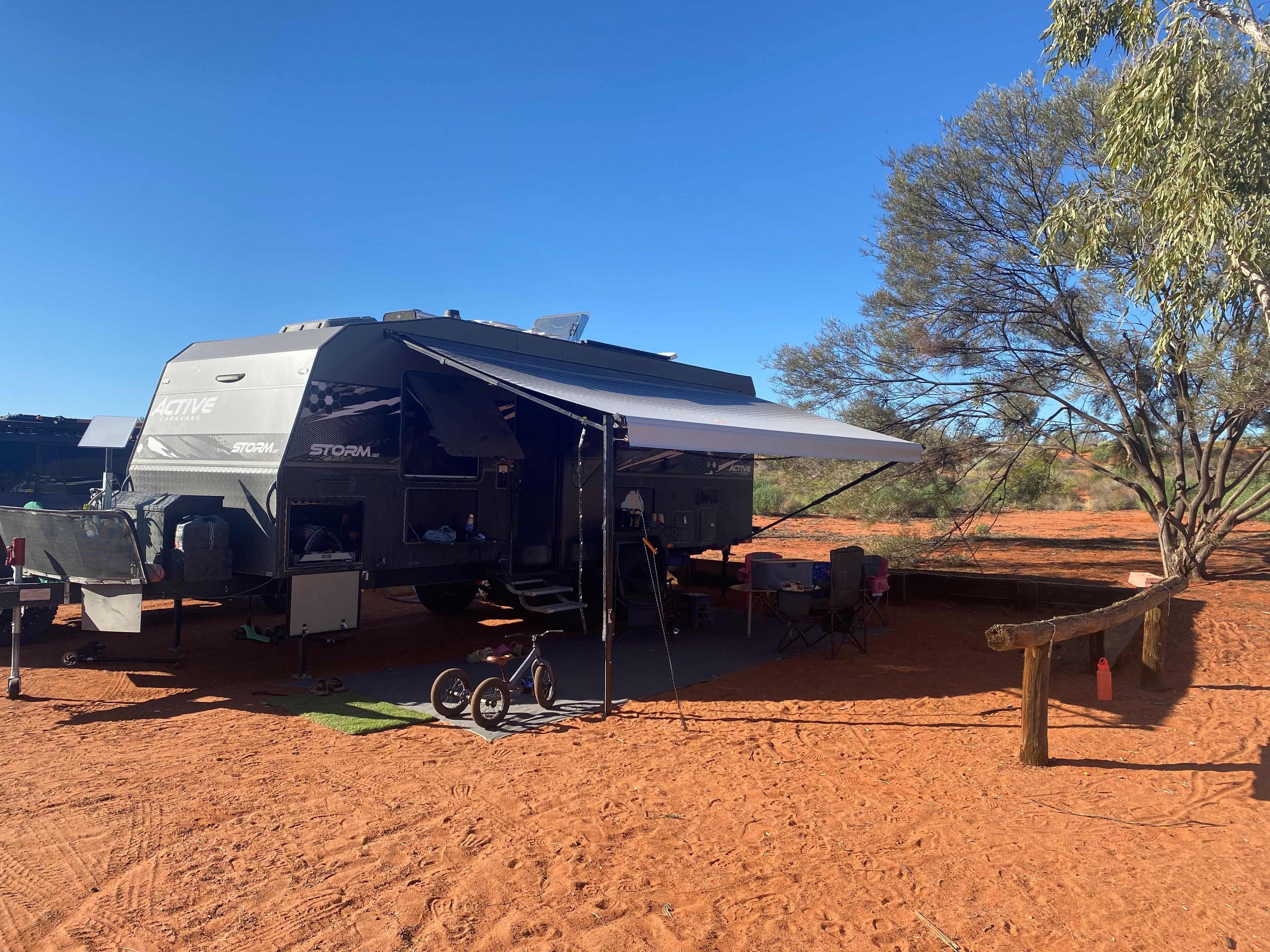 Caravan set up on a powered site with red dirt