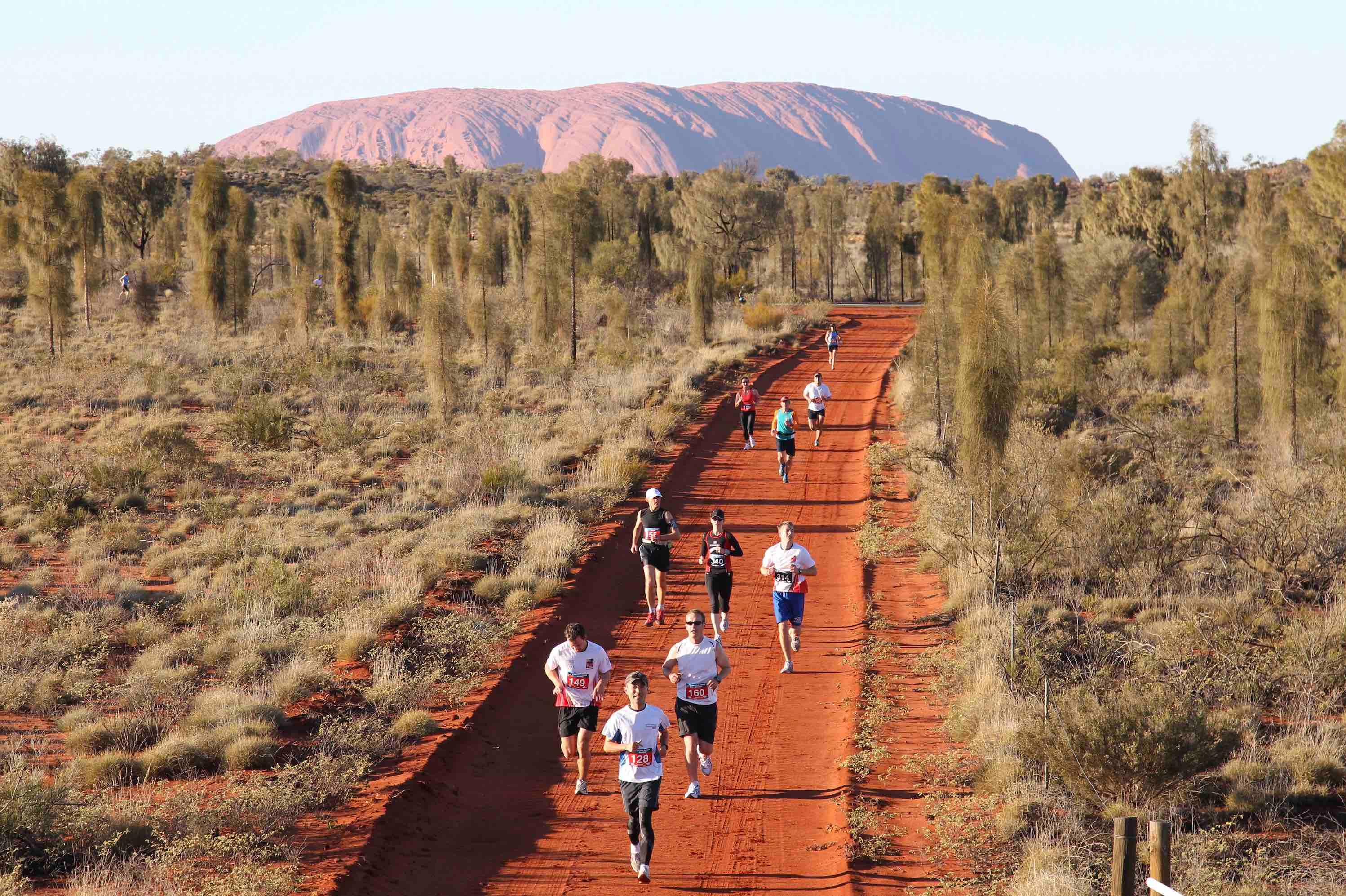 Runners compete in the Australian Outback Marathon with Uluru in the background