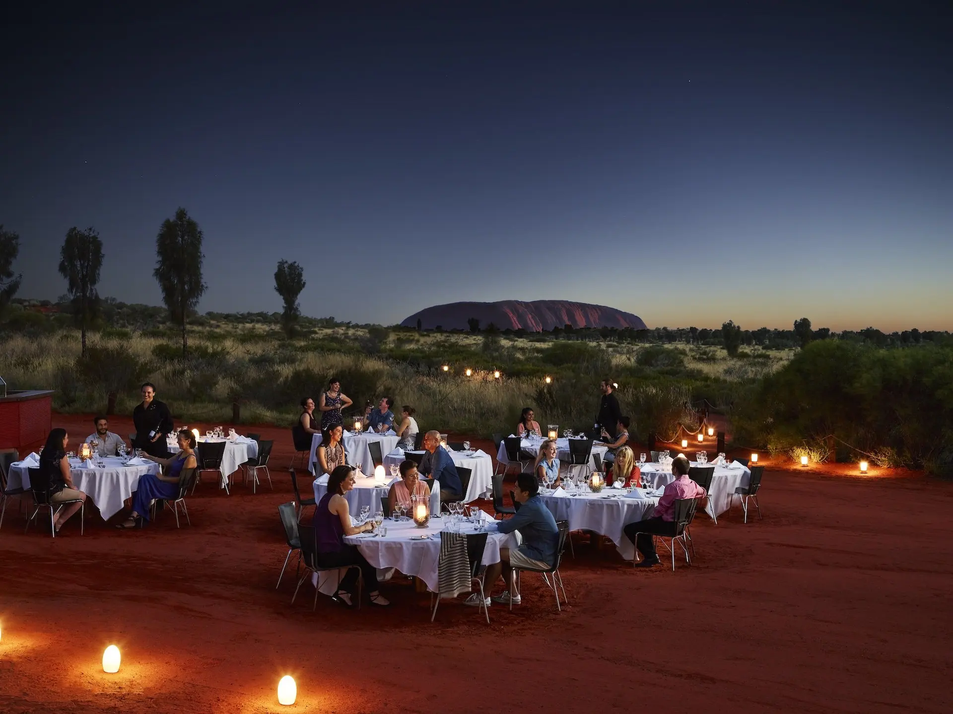 Diners at white-linen tables dining outdoors near Ayers rock