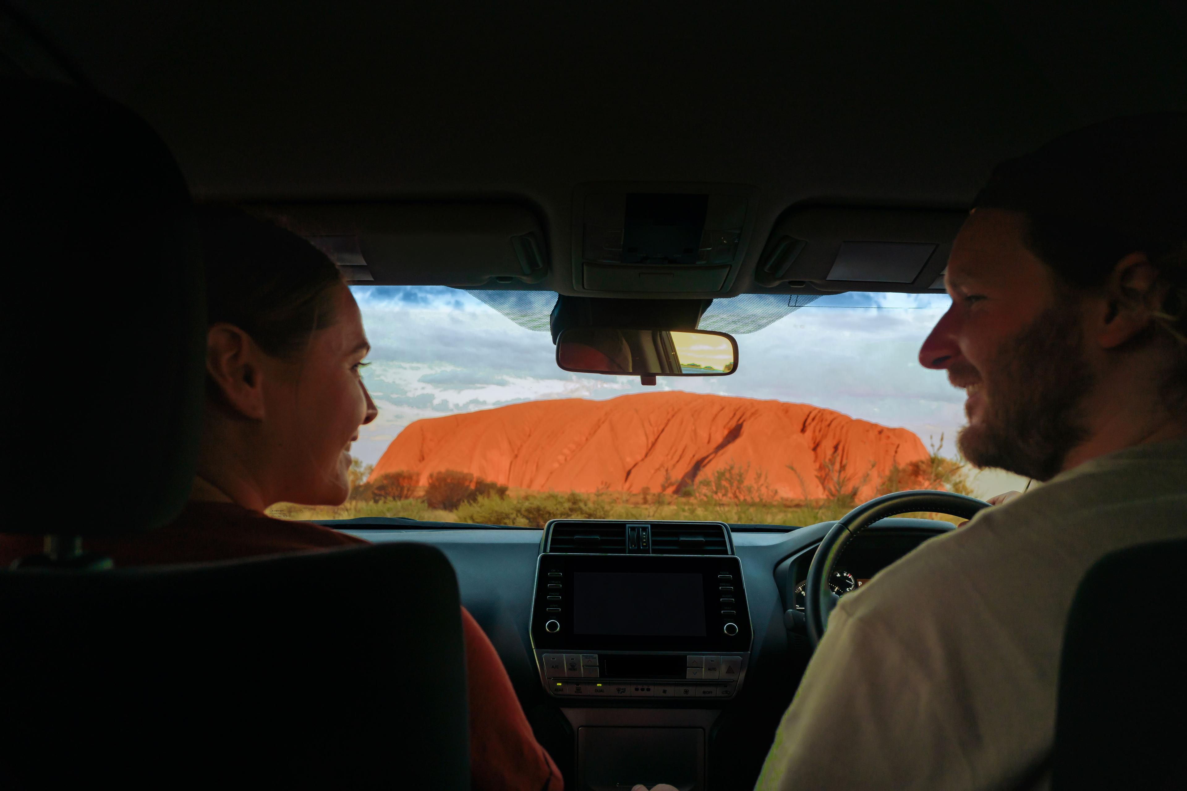 young_couple_in_car_looking_at_uluru