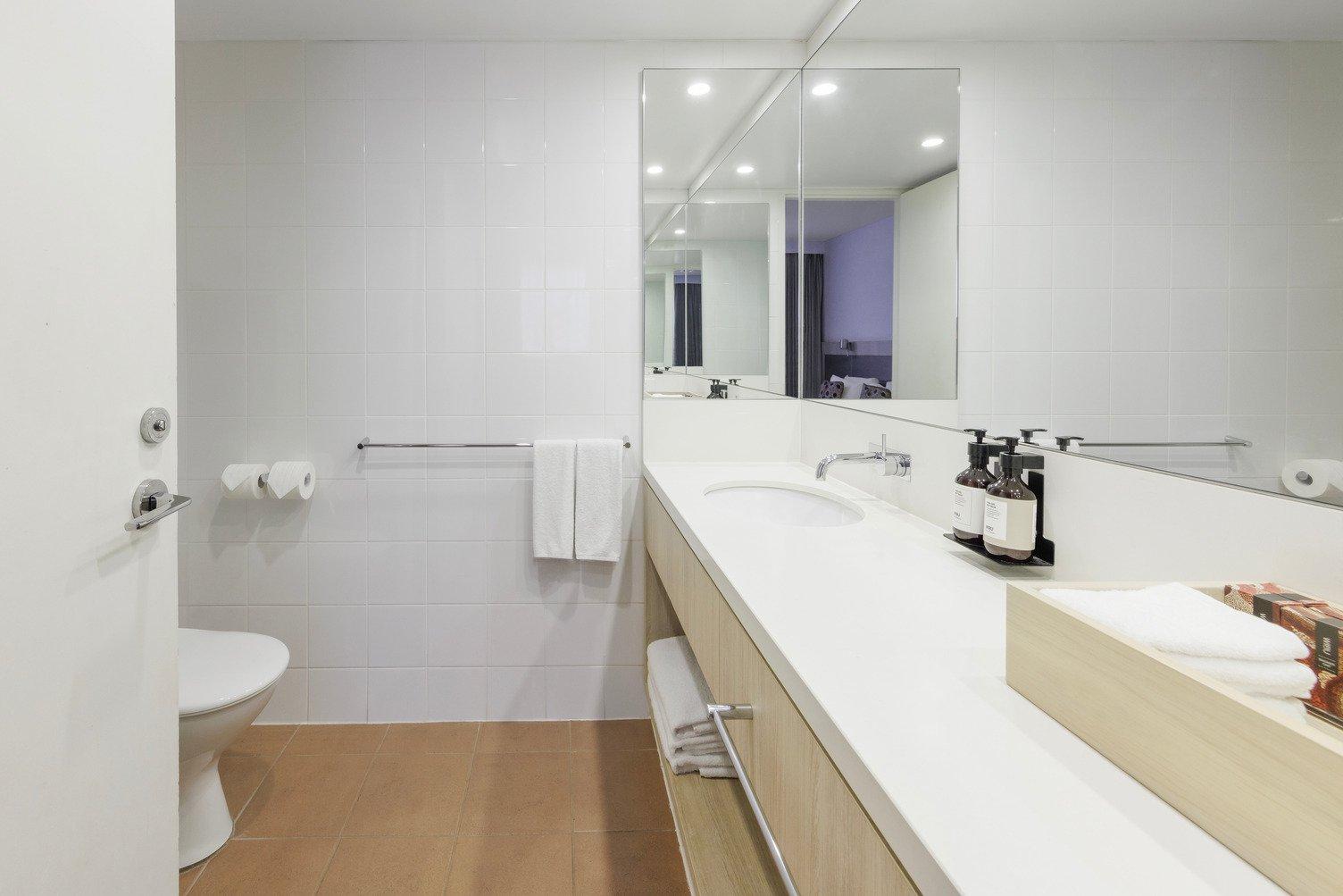 Looking into Ensuite from bedroom with long cabinet, shower, toilet, wiru products and sink