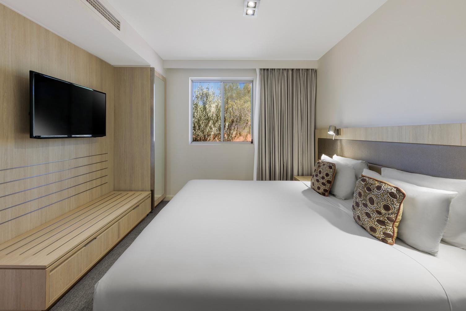 Bed with TV mounted to wall and window with long curtains