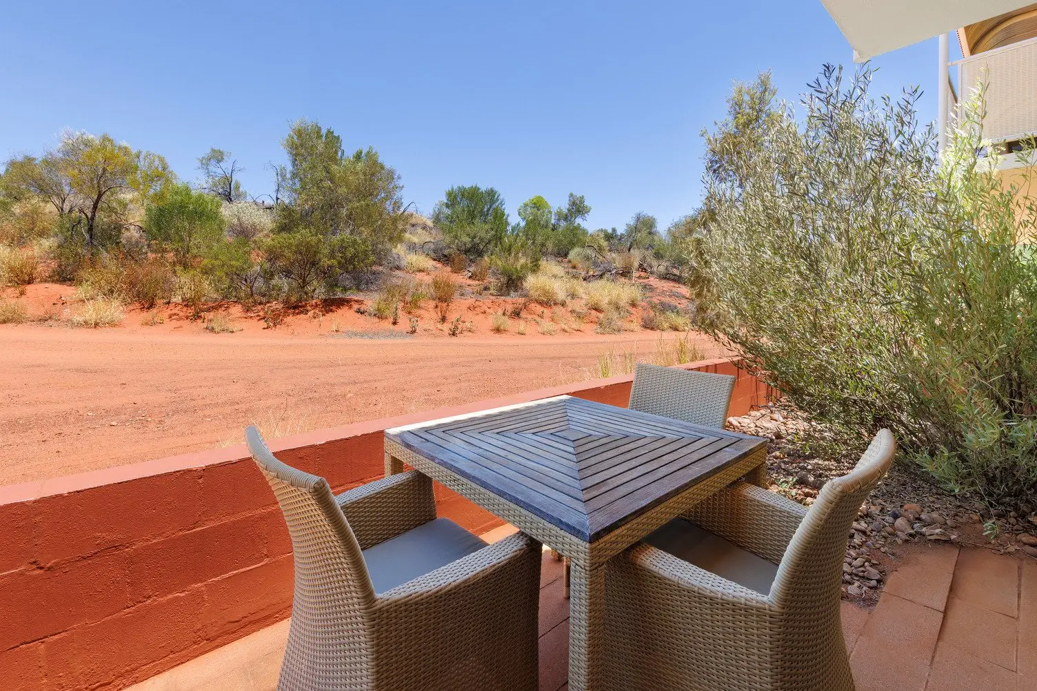 Courtyard with three chairs and garden looking out onto the red desert landscape