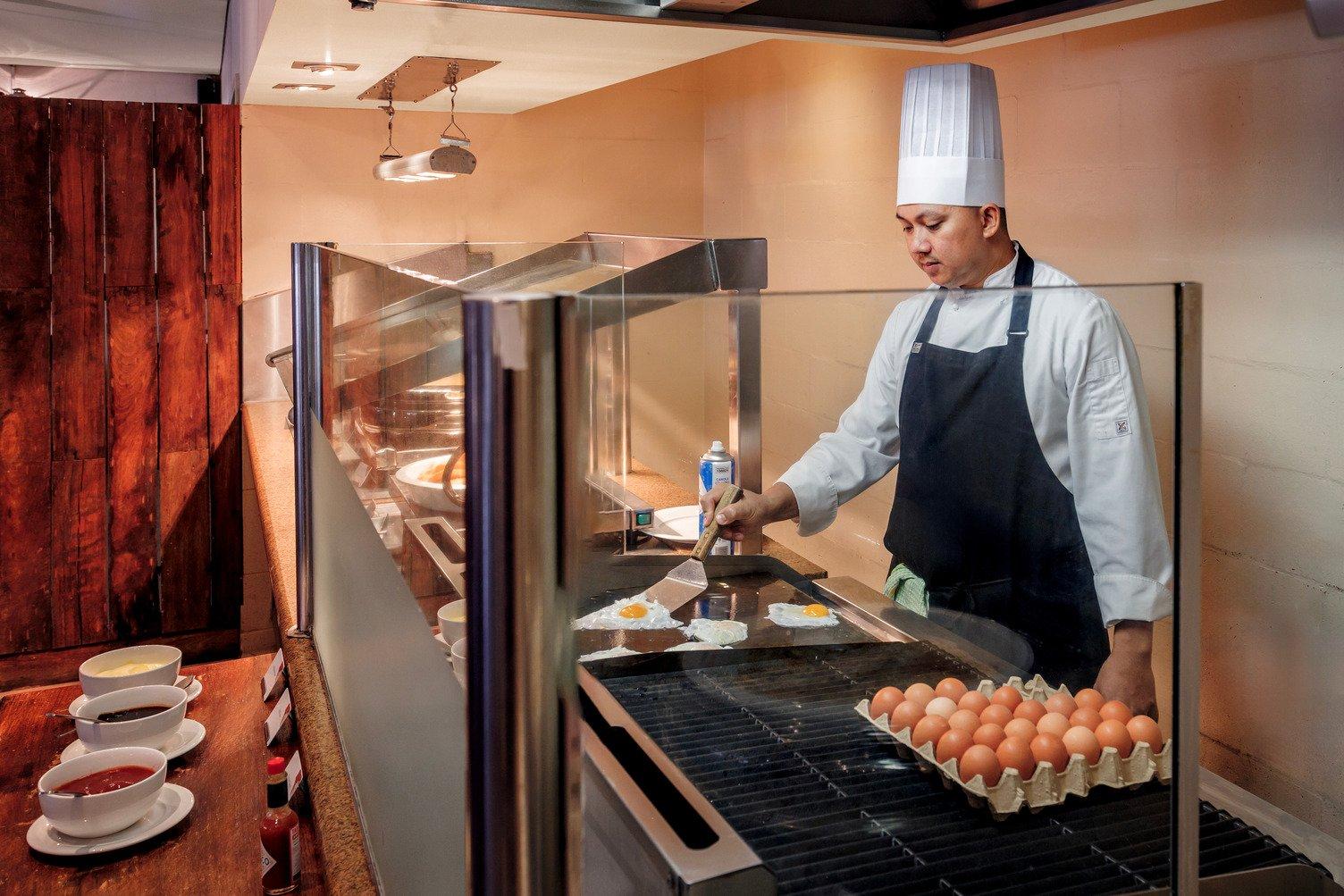 A Chef dresses in a chefs apron and hat frying an egg at the egg station in Bough House restaurant