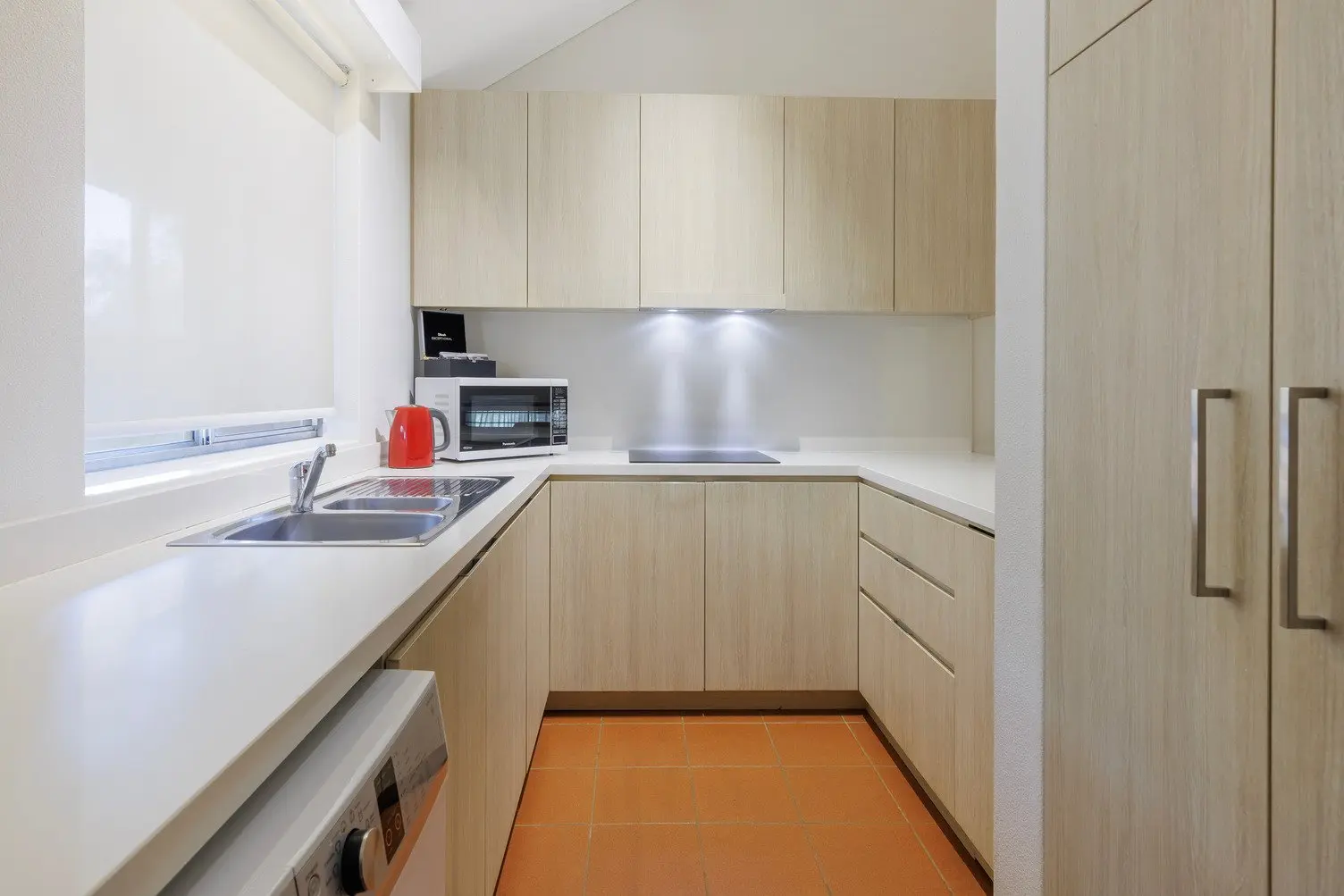 Kitchen with laundry, sink, dishwasher, cooktop and microwave