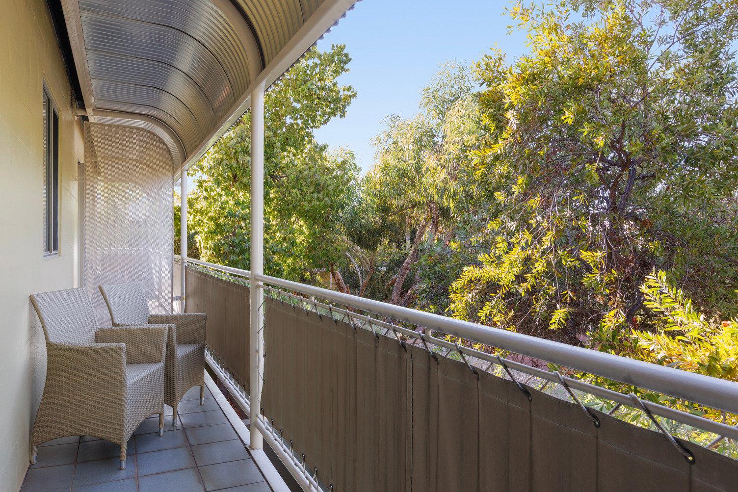 Balcony looking out onto the garden with two outdoor chairs