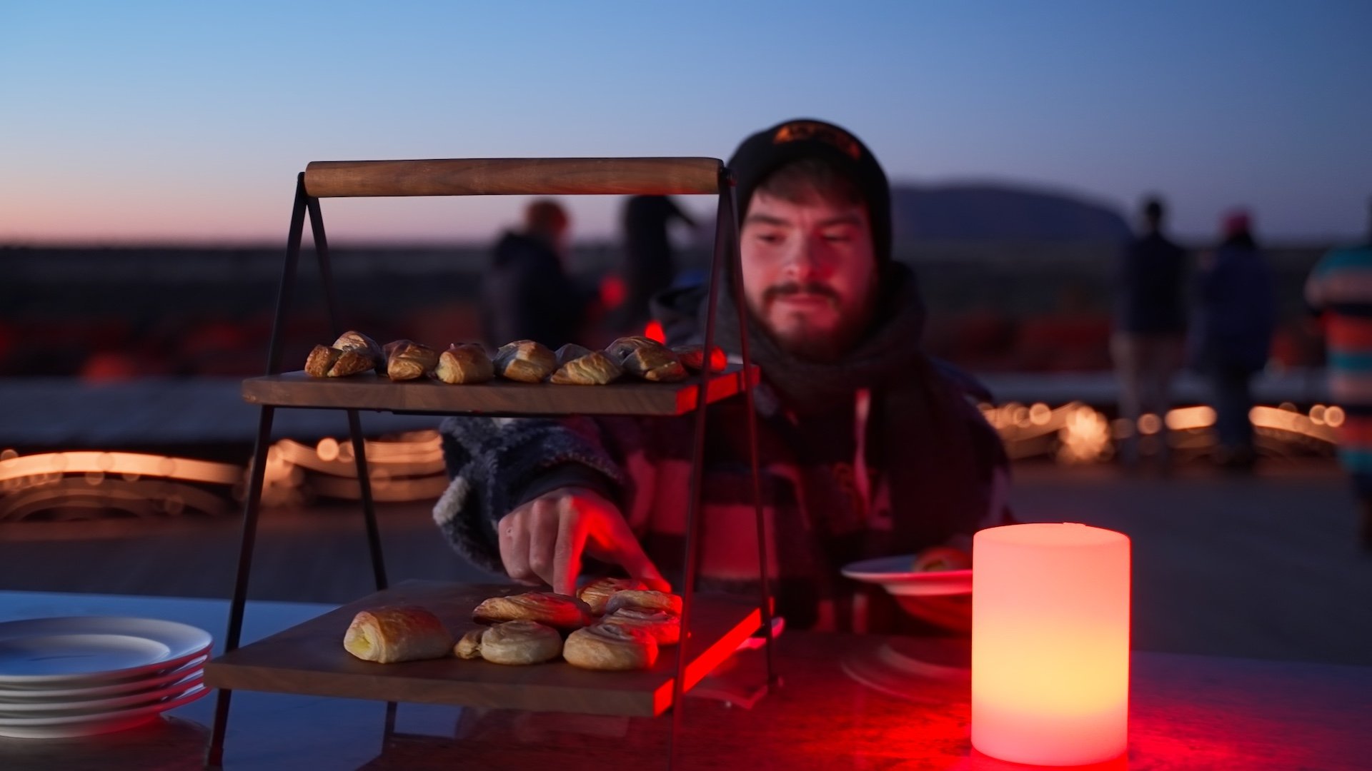 A man chooses a breakfast pastry at an outdoor sunrise breakfast