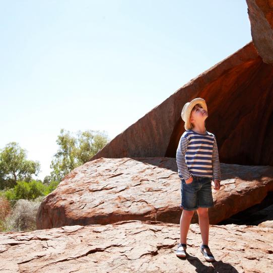 Young boy in hat and striped shirt looking at Ayers Rock