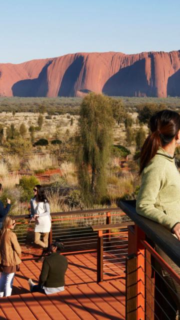 people on a deck with Ayers Rock in the background