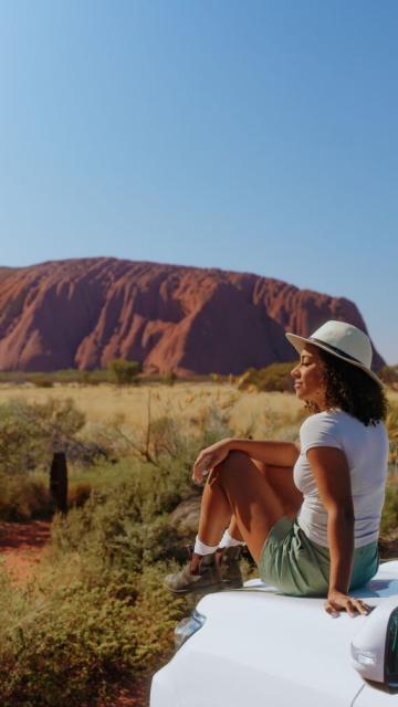 women-sitting-on-top-of-the-car-watching-uluru